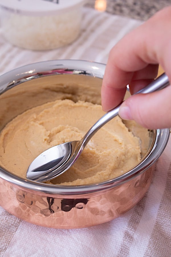adding hummus to copper bowl and smoothing with spoon