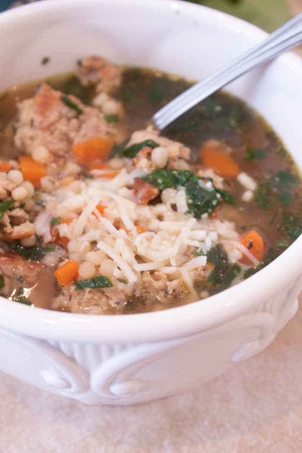 a bowl of Italian wedding soup in a white ceramic bowl