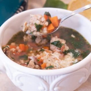 white bowl of Italian wedding soup with a spoonful propped up