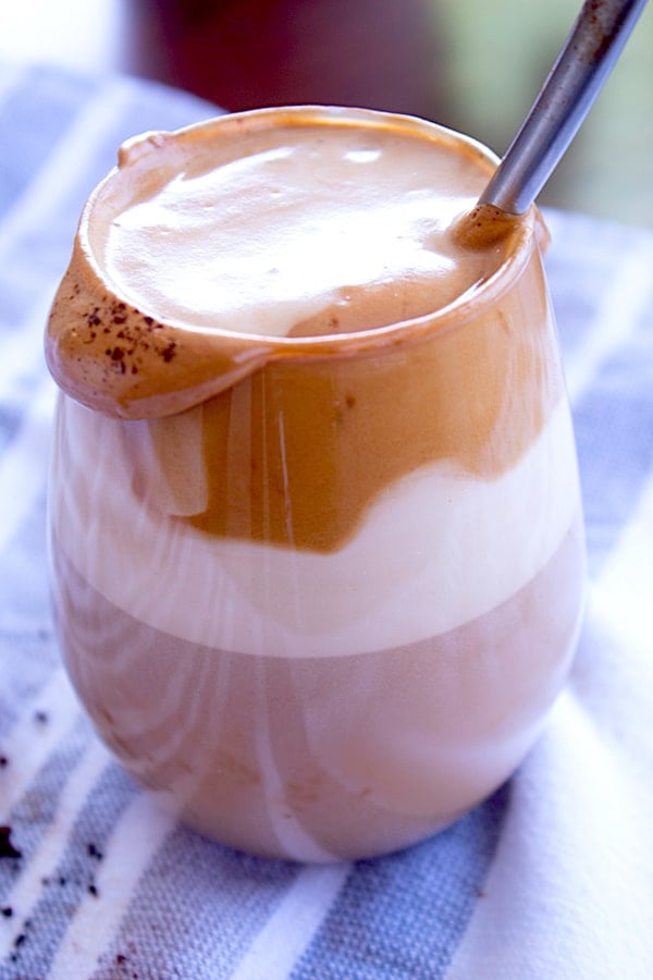 whipped coffee in a glass layered with milk