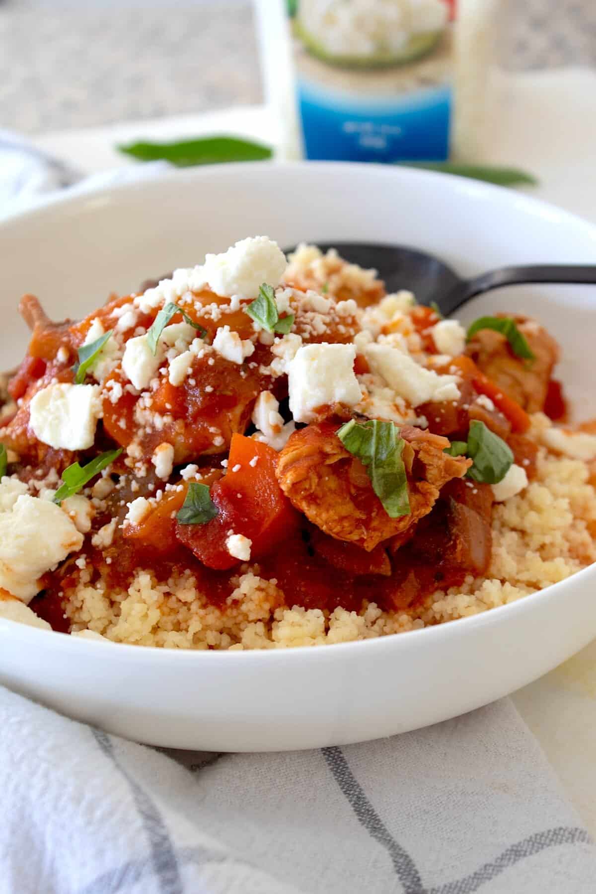 side view of morrocan chicken stew in a white bowl with feta cheese