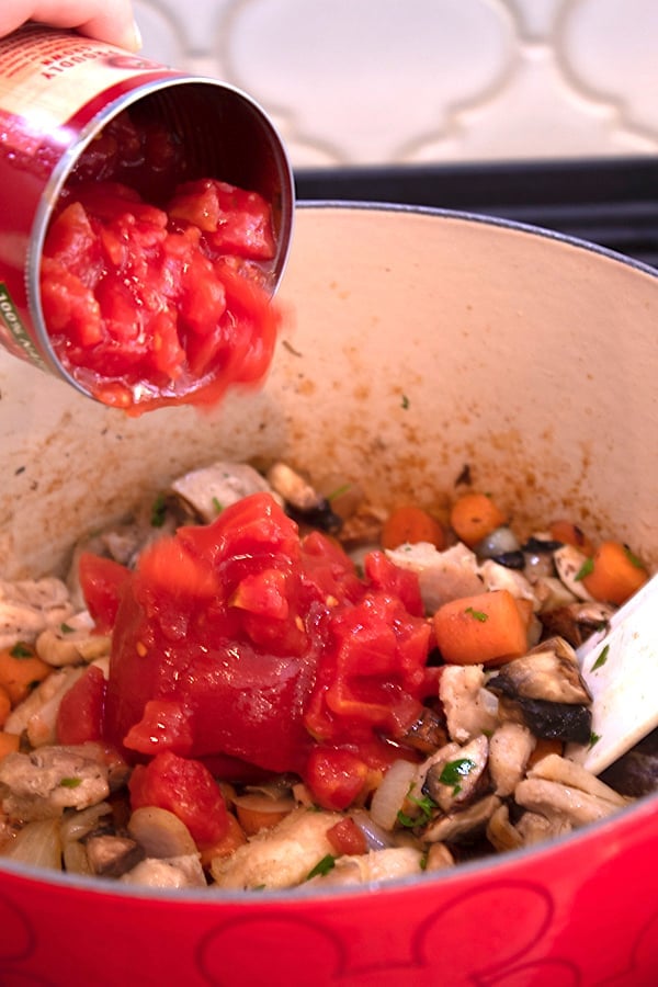 adding canned tomatoes to stew