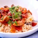 moroccan chicken stew in white dish over couscous
