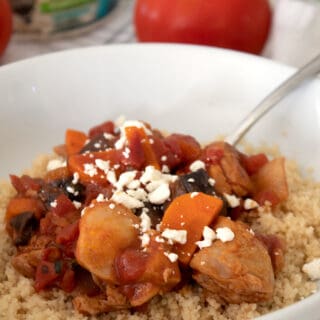 moroccan chicken stew over couscous with feta cheese in white bowl