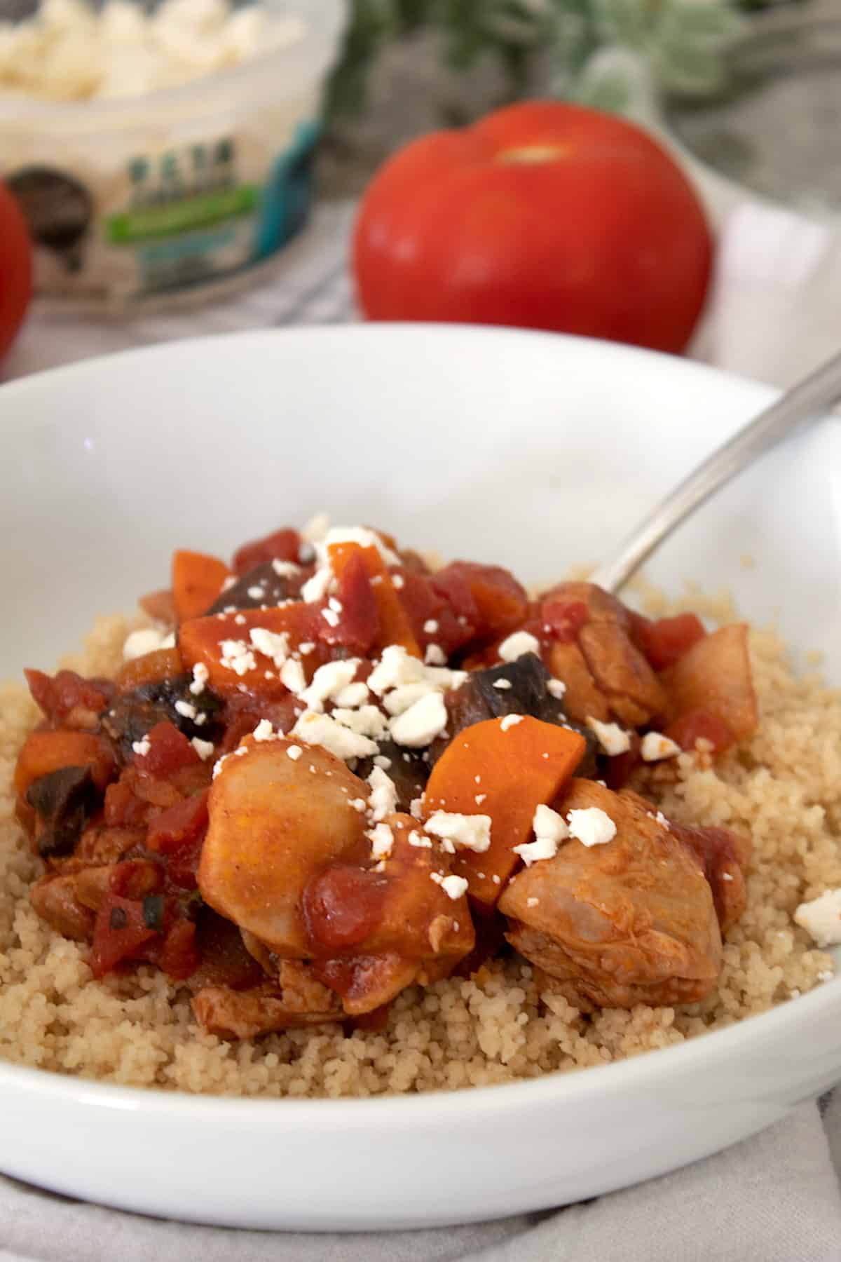 moroccan chicken stew over couscous with feta cheese in white bowl