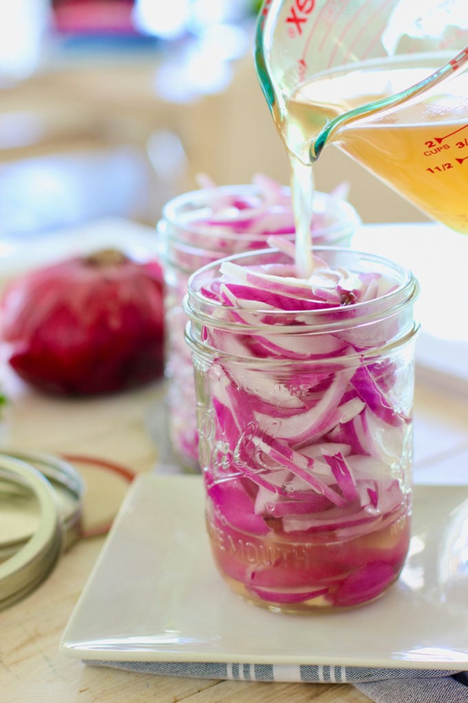 pour apple cider vinegar brine over sliced purple onion