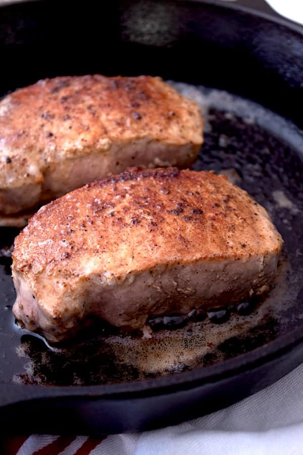 2 seared pork chops in a cast iron skillet