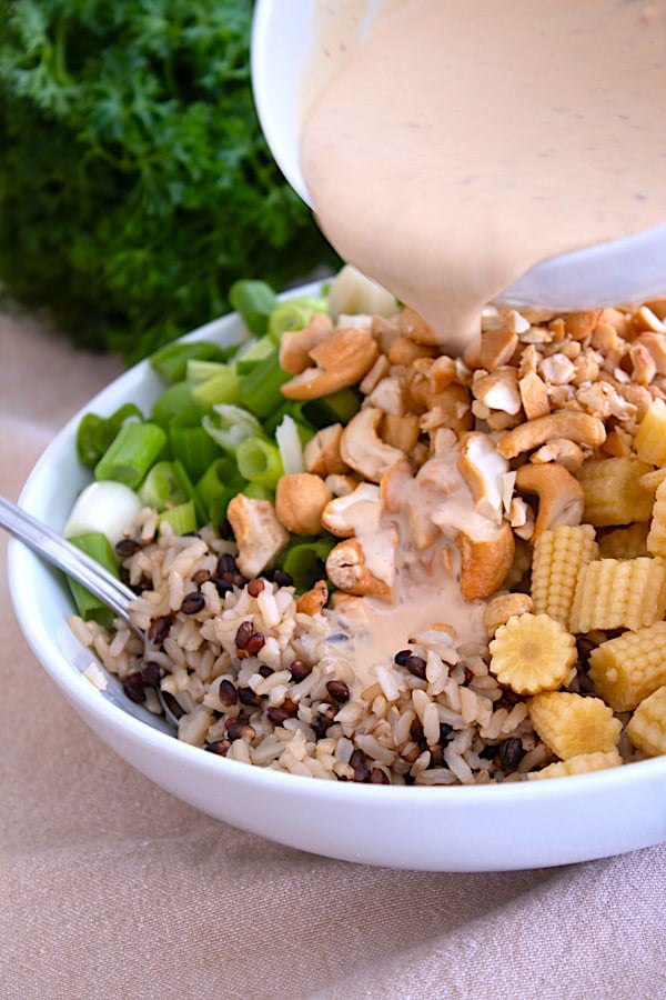 pouring dressing on asian rice salad