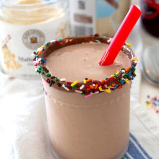 chocolate malt in a chilled clear glass with chocolate sprinkle rim and a red straw