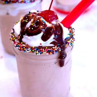 chocolate malt with sprinkles chocolate sauce and red straw with a cherry on top