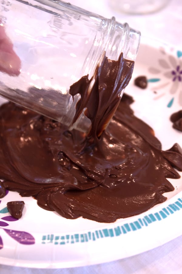 dipping mason jar in melting chocolate on a paper plate