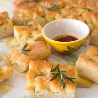 close up of focaccia bread with a small yellow dish full of oil and balsamic