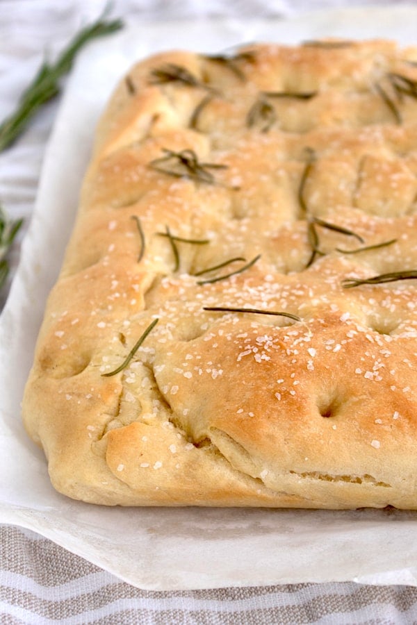 rosemary focaccia bread out of the oven on a white parchment sheet