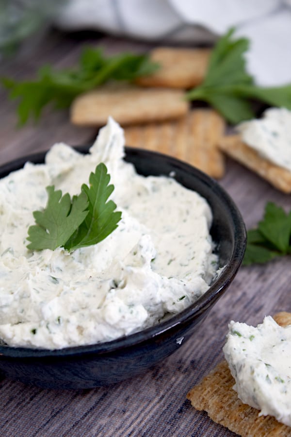 homemade Boursin cheese in black dish with trisect crackers and parsley garnish