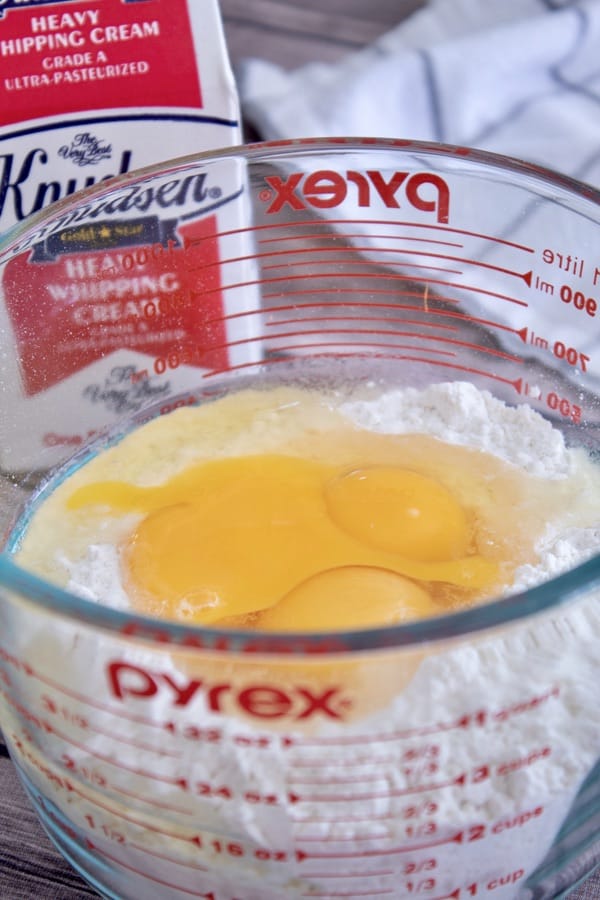 mixing flour, eggs and heavy whipping cream in a pyrex mixing bowl
