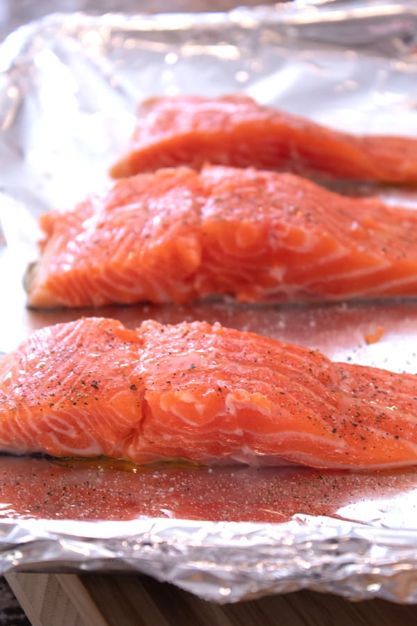 salt and pepper coated salmon on a foil lined sheet pan 