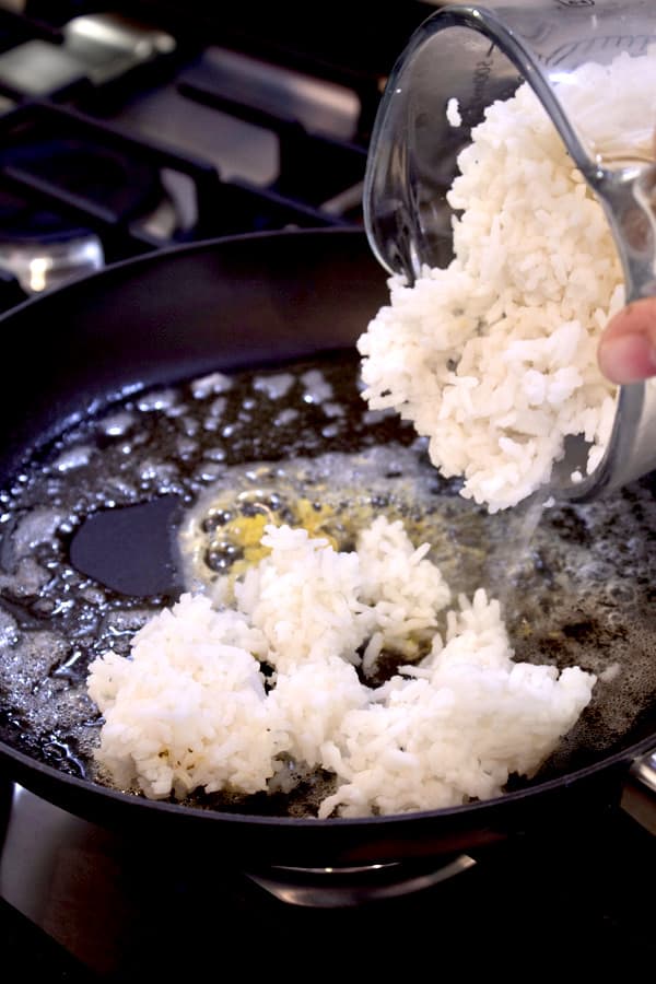 adding white rice to skillet with butter garlic and lemon zest