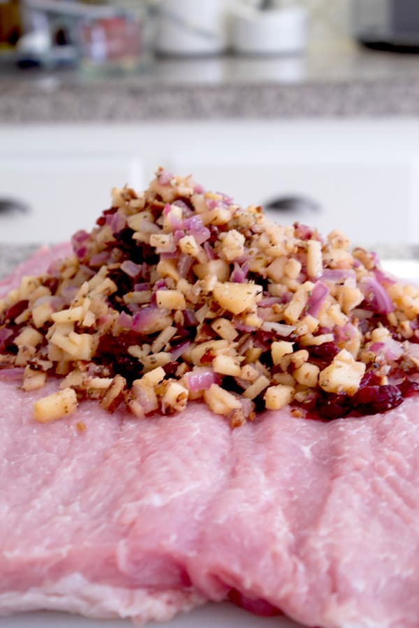 adding stuffing on top of pork loin roll 