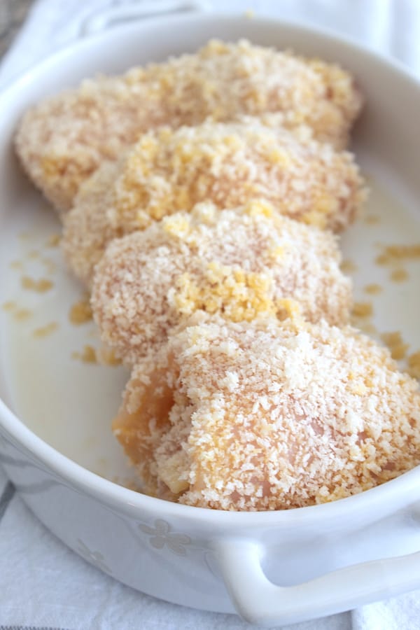 chicken coated in panko crumbs in white casserole pan