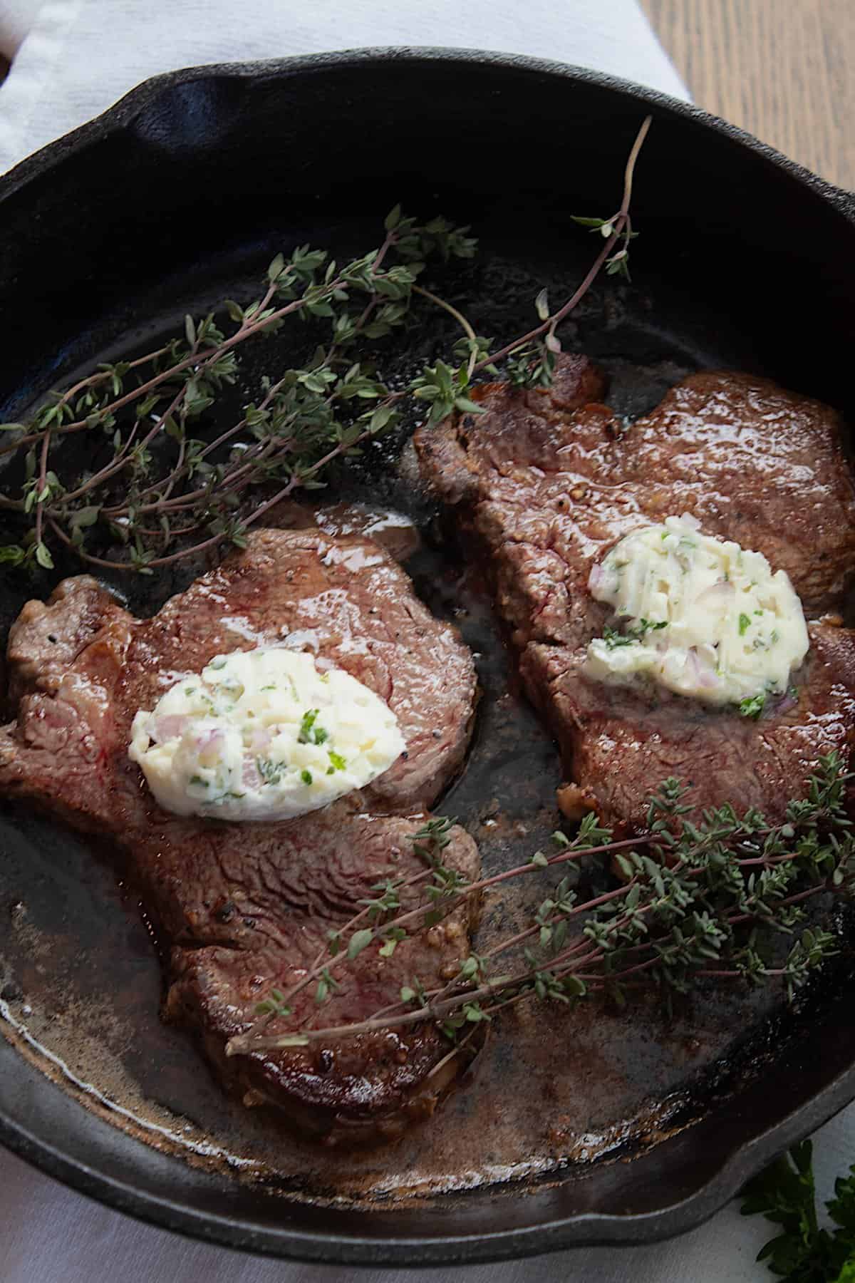 overhead view of steak in a pan with compound butter