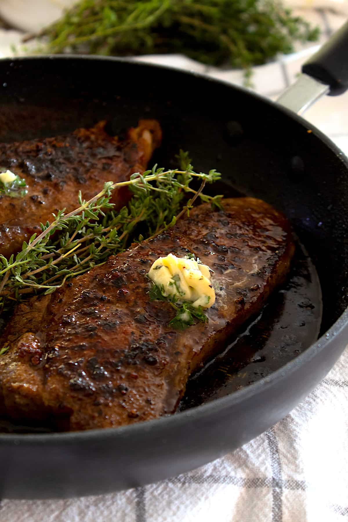 steak seared in a pan with herbs and compound butter