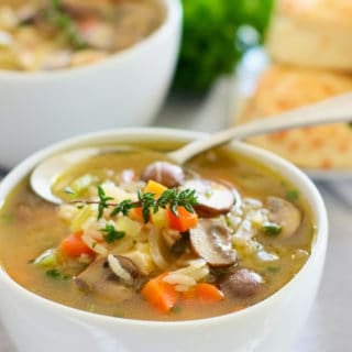 chicken and mushroom soup in a white bowl with spoon