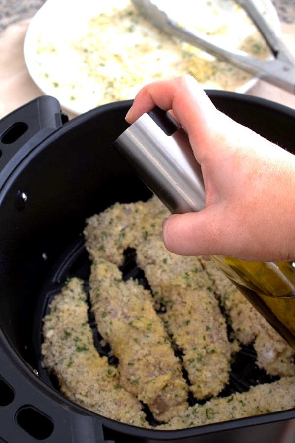 spraying olive oil on chicken tenders