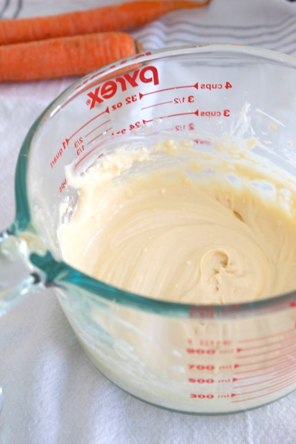 a pyrex clear bowl with cream cheese frosting mixed in it