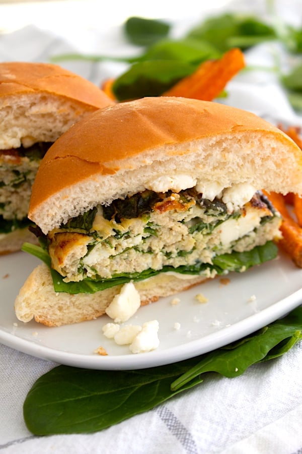 spinach feta burger in half on plate with sweet potato fries