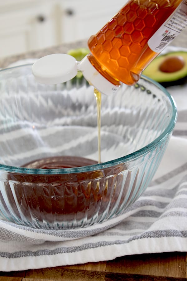 mixing bbq sauce with honey in clear glass bowl