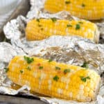 corn on the Cobb on foil on a sheet pan garnished with parsley