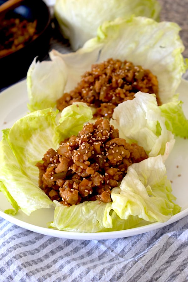 lettuce wraps with chicken filling on a white plate