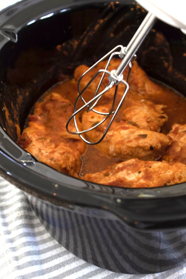 chicken in a slow cooker with hand mixer to shred 
