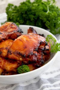 bbq chicken in a white dish with parsley garnish