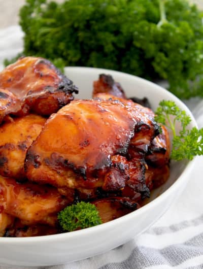 bbq chicken in a white dish with parsley garnish