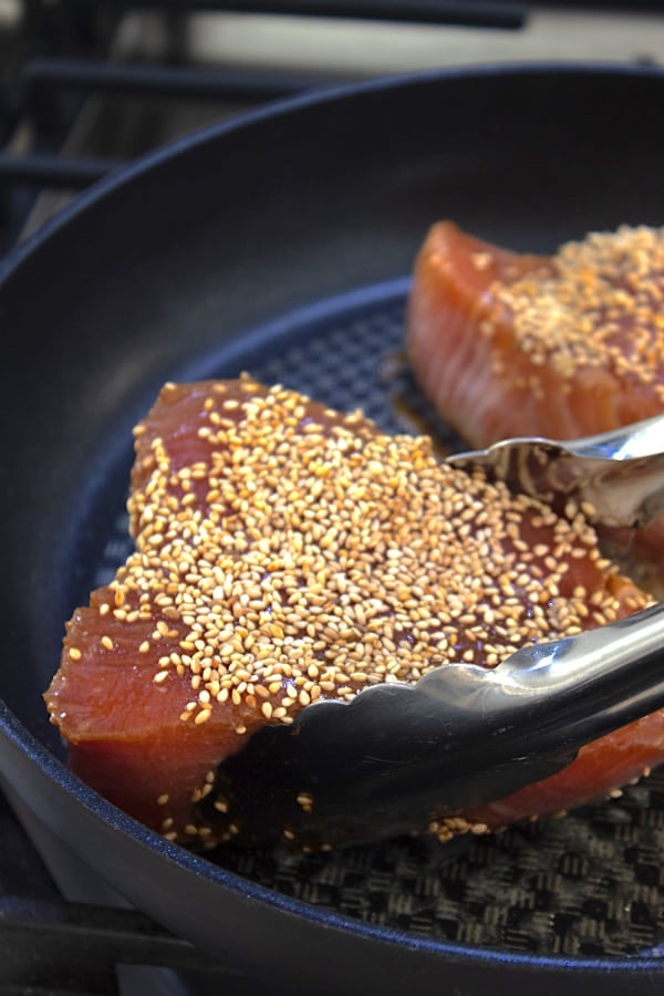 preheated pan with ahi tuna steaks being added