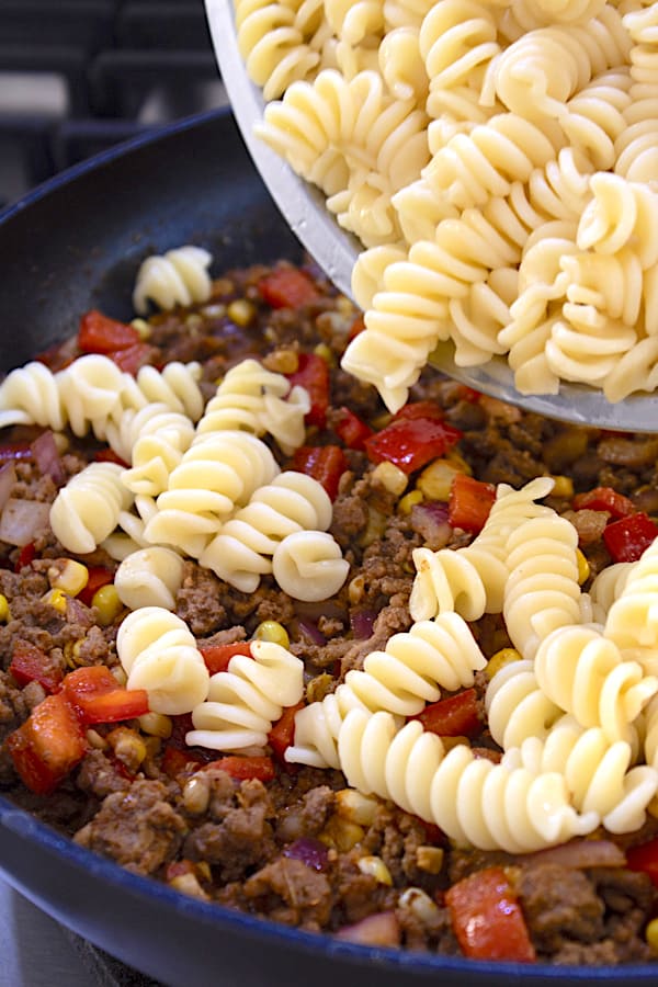 adding boiled pasta to beef mixture