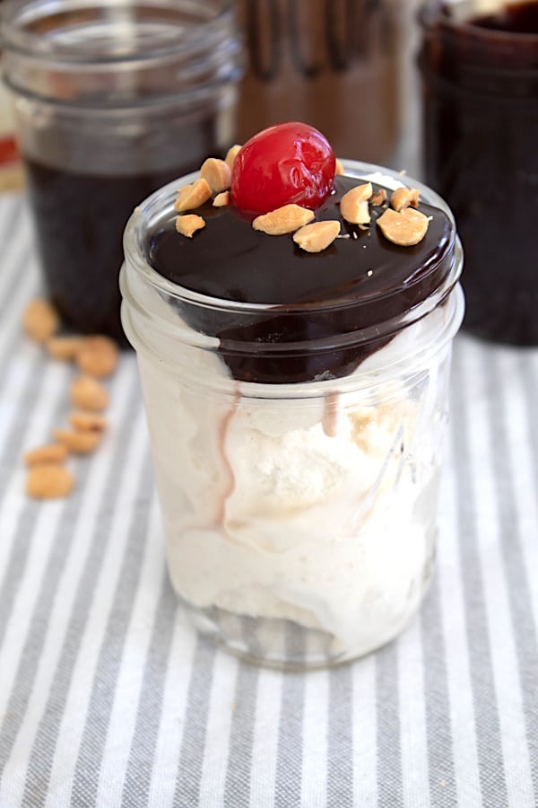 Hot Fudge over vanilla ice cream in a mason jar with cherry and nuts on top