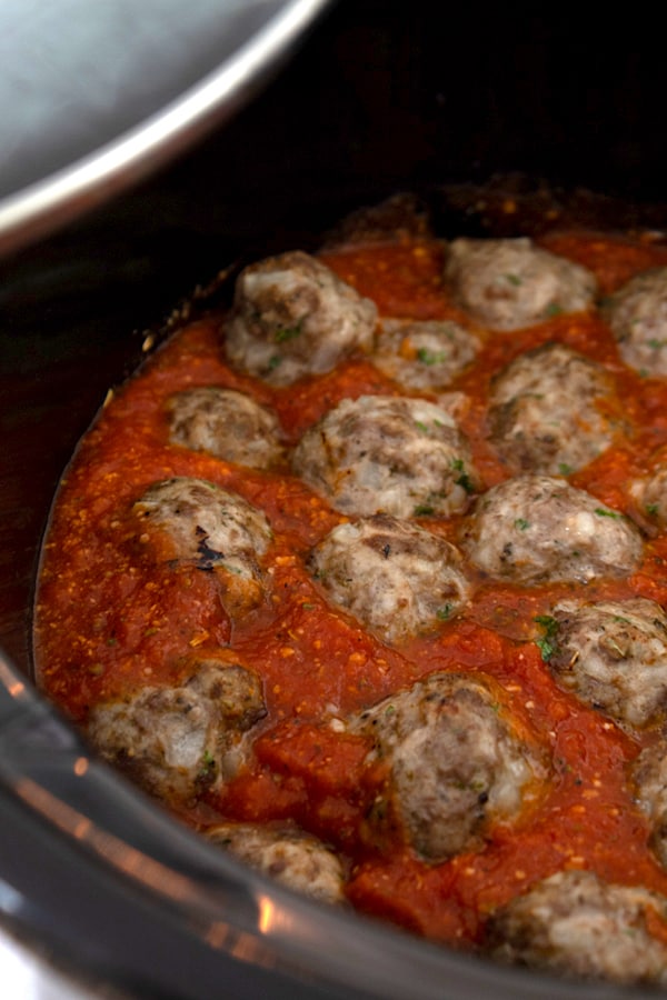 placing meatballs in slow cooker in marinara sauce