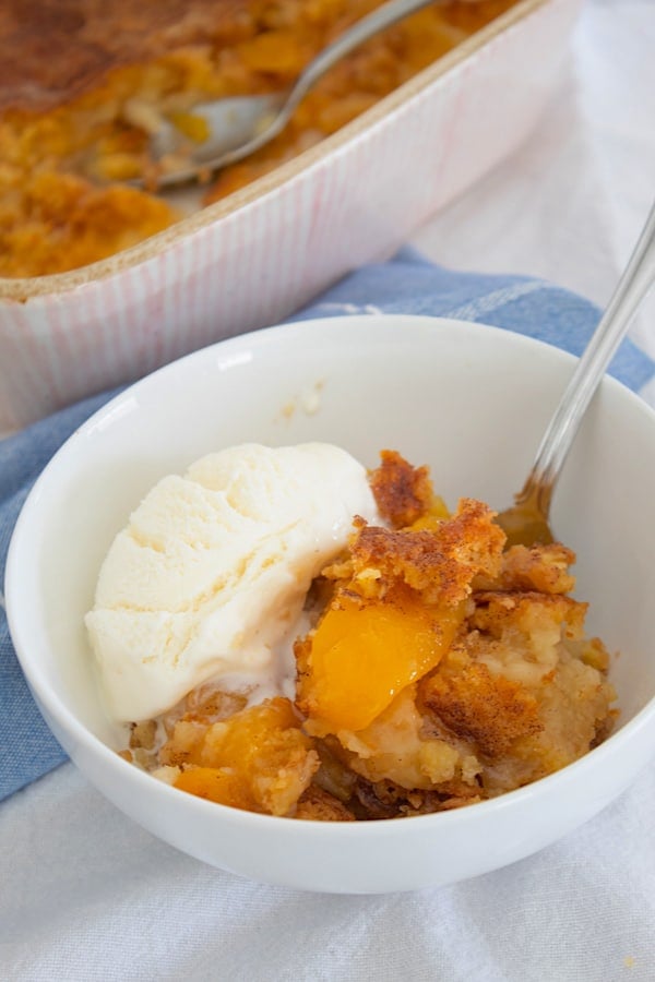 bowl of peach dump cake with ice cream