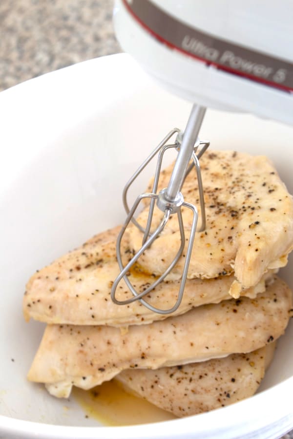 chicken breasts in bowl with hand mixer