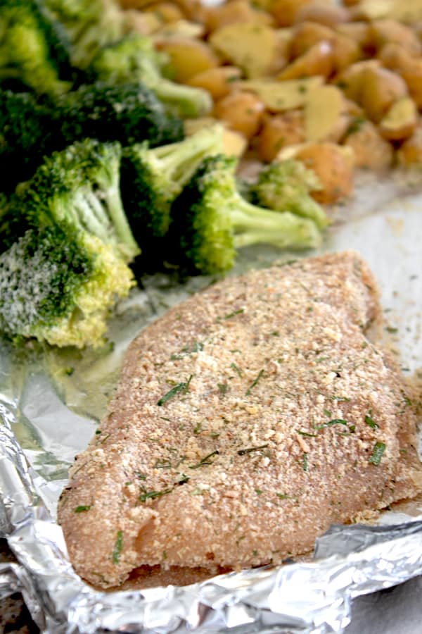 raw chicken broccoli and potatoes on a a sheet pan with ranch seasoning 