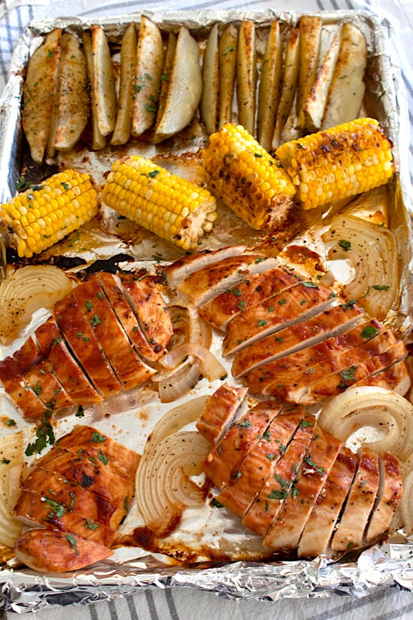 overhead view of sheet pan chicken dinner with corn and potato wedges