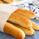 breadsticks wrapped in parchment paper on a blue kitchen dish towel