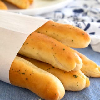 breadsticks wrapped in parchment paper on a blue kitchen dish towel