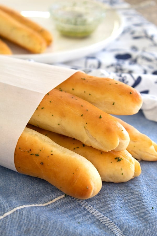 breadsticks wrapped in parchment paper on a blue kitchen dish towel