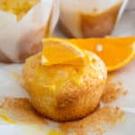 orange muffin out of its wrapper garnished with an orange slice