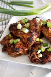 marinated chicken thighs on a plate garnished with green onion