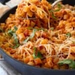 spoonful of ground chicken pasta in a black pan