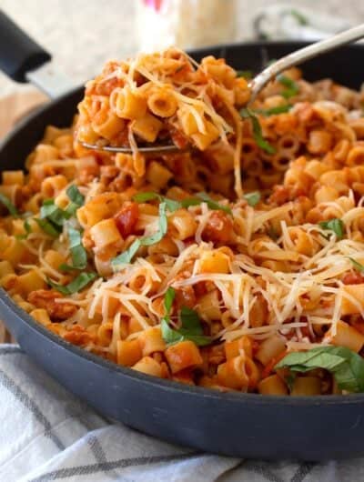 spoonful of ground chicken pasta in a black pan